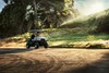 Three-quarter front angle of a person driving a side x side on a dirt road.