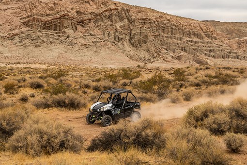 Three-quarter front angle of a person driving a side x side off-road. opens in a new window