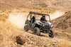 Three-quarter front angle of a person driving a side x side on a dirt trail.