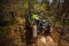 Three-quarter front angle of a person driving a side x side through rugged terrain.