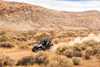 Distant, three-quarter front angle of a person driving a side x side off-road.