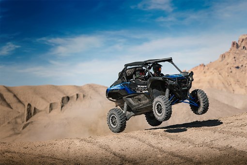 Three-quarter front angle of a person catching air in a side x side off-road. opens in a new window