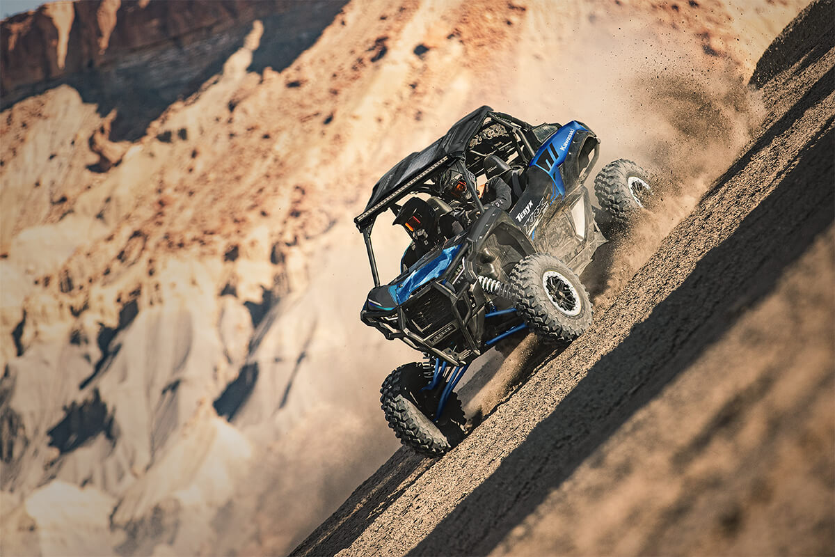 Three-quarter front angle of a person driving down a steep hill in a side x side off-road.