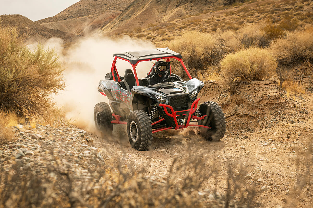 Three-quarter front angle of a person driving a side x side off-road.