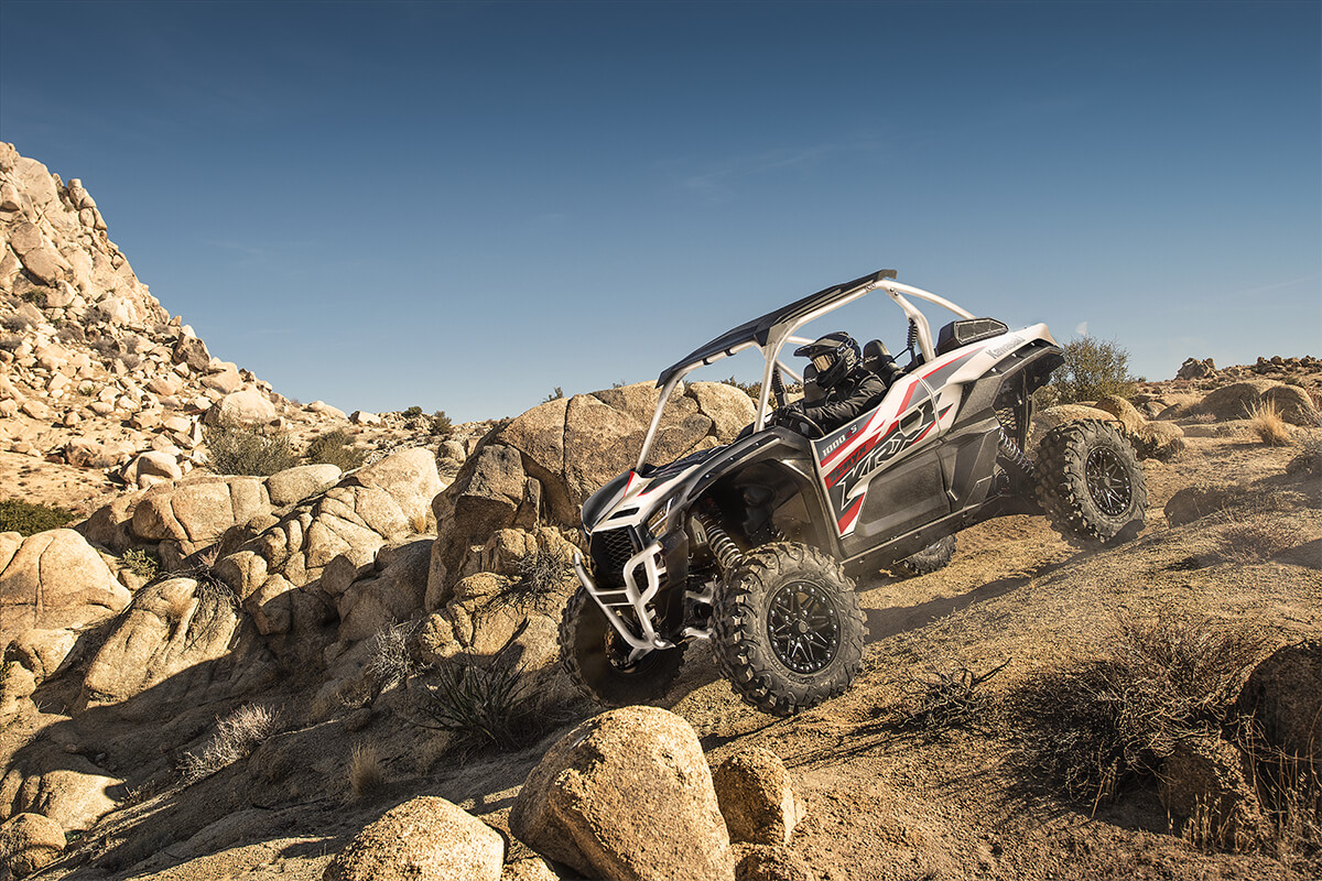Three-quarter front angle of a person driving a side x side off-road.