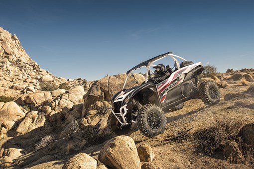 Three-quarter front angle of a person driving a side x side off-road. opens in a new window