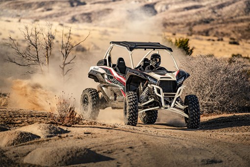 Three-quarter front angle of a person coming out of a turn in a side x side off-road. opens in a new window