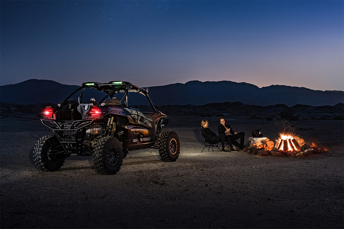 Three-quarter rear angle of a side x side off-road at night next to a bonfire.