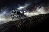 Three-quarter front angle of a person driving a side x side with lights on off-road at night.