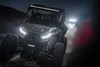 Front angle of a side x side driving off-road at night with another side x side in the background.
