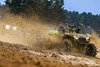 Three-quarter front angle of a side x side driving off-road with another side x side in the background..