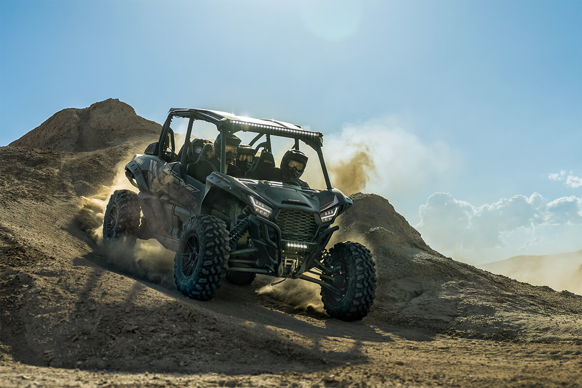 Three-quarter front angle of a side x side driving off-road down a hill in the desert.