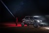 Three-quarter front angle of a side x side with lights on parked off-road at night.