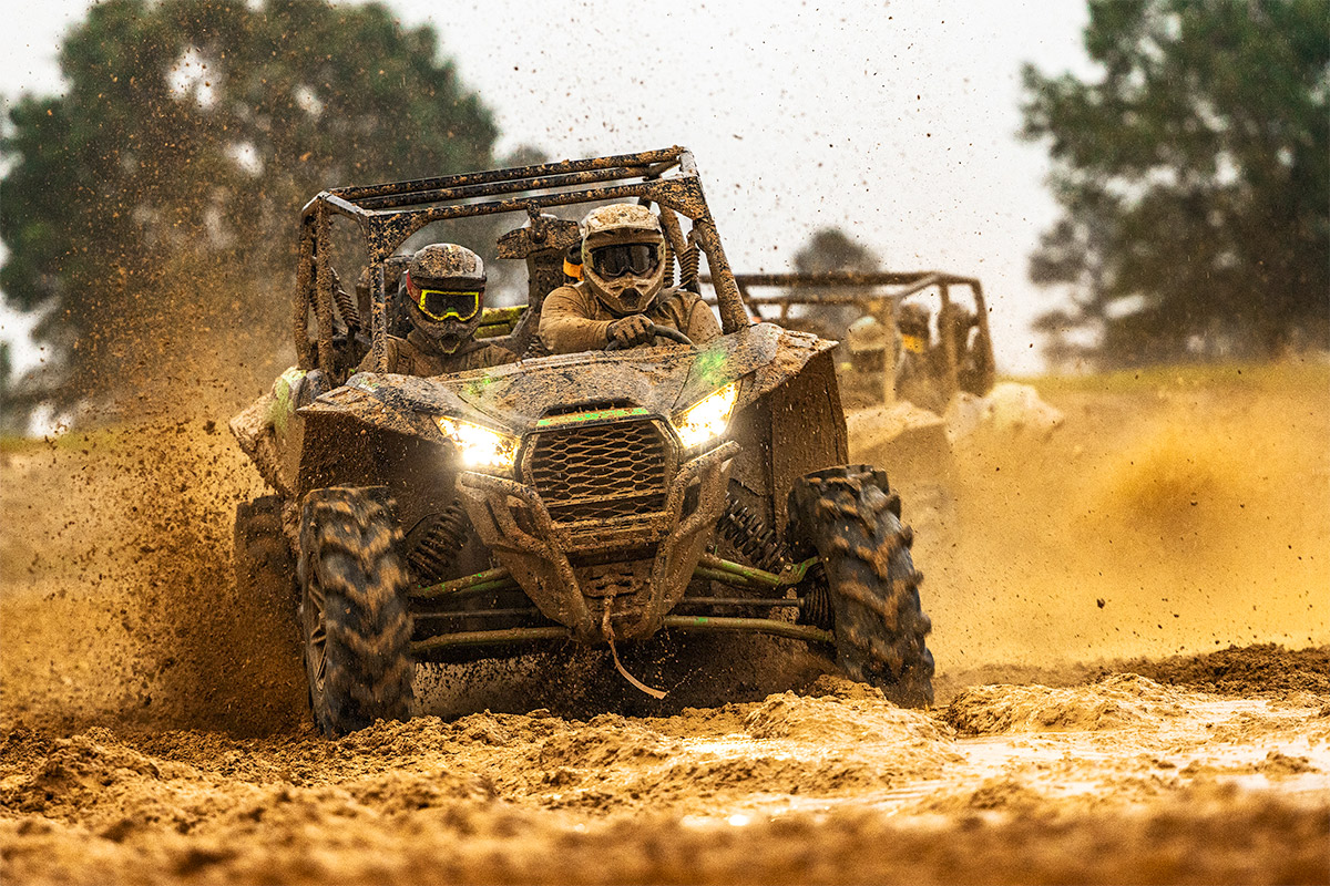 Front angle of a side x side driving off-road with another side x side in the background.