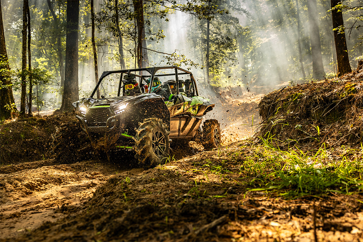 Three-quarter front angle of a side x side driving in the forest.