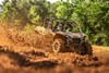 Three-quarter front angle of a side x side kicking up mud off-road.