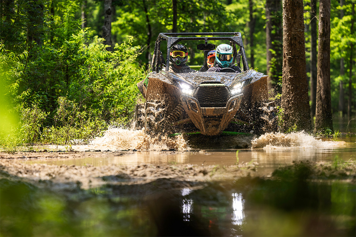 Front angle of a side x side driving through shallow water off-road.