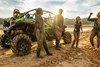 Three-quarter rear angle of a side x side off-road with people standing around.
