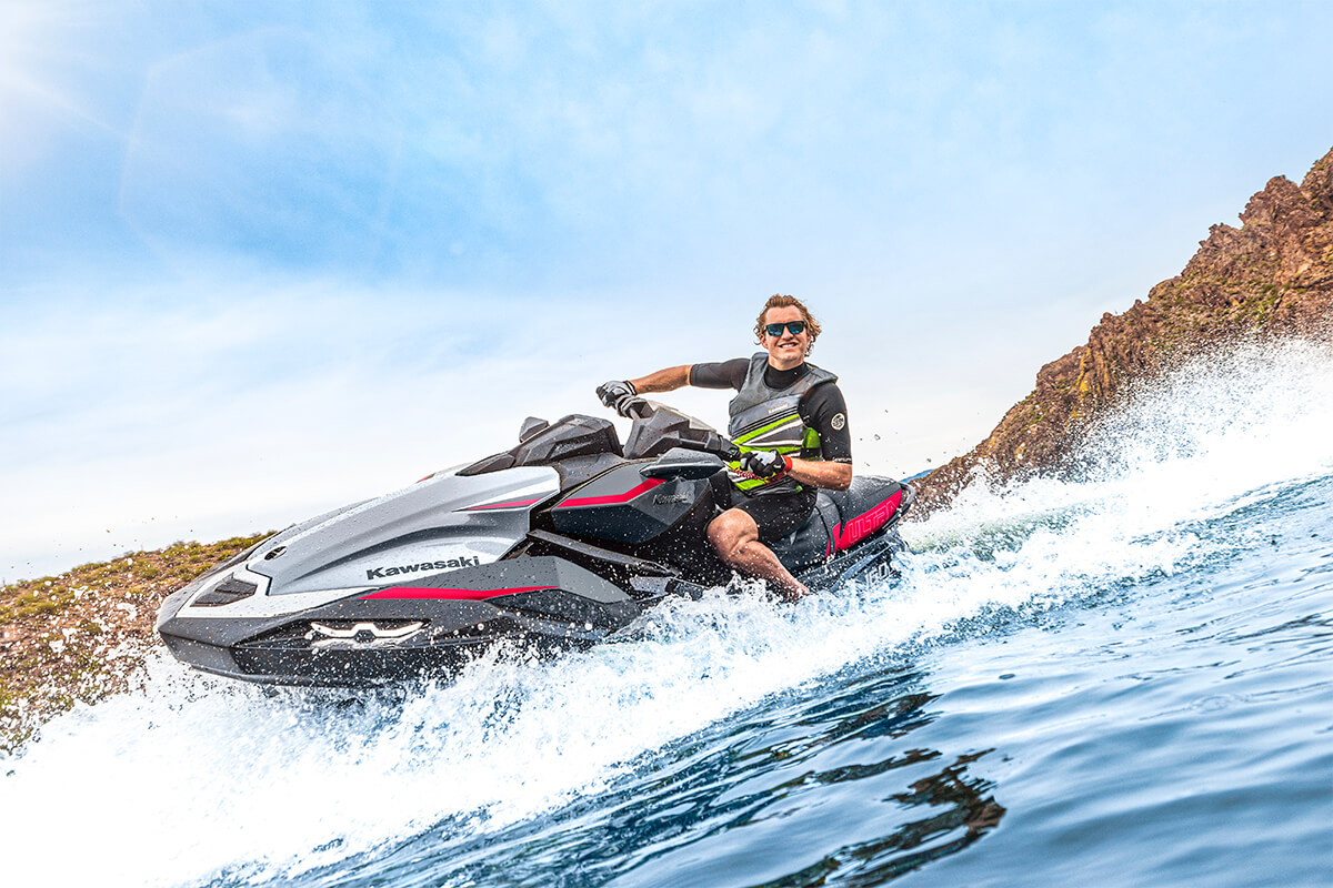 Close-up, three-quarter front angle of a person on a personal watercraft on the water. 