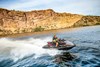 Side angle of a person on a personal watercraft on the water.