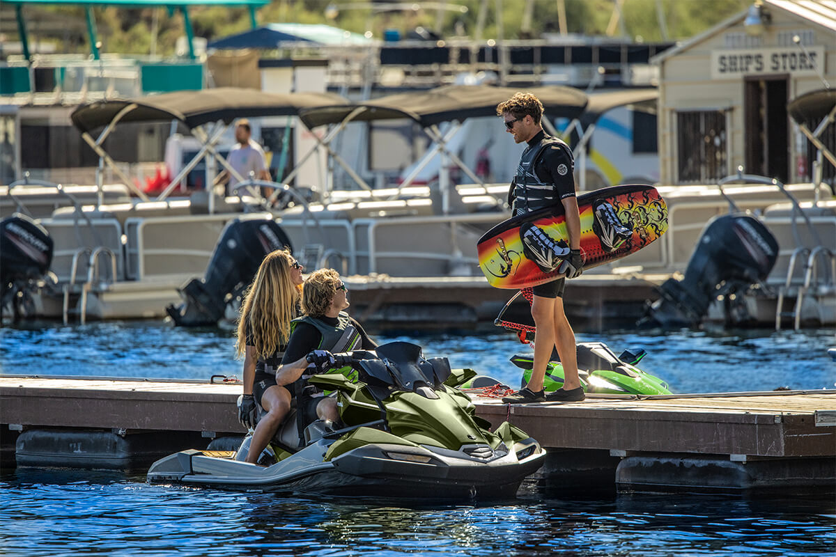 Three-quarter front angle of a person sitting on a docked personal watercraft on the water.