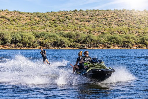Three-quarter front angle of a person on a personal watercraft pulling a water skier on the water. opens in a new window