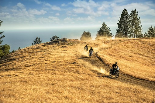 Front angle of three motorcycles riding on a dirt trail. opens in a new window