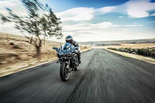 Front angle of a person riding a motorcycle on a road. opens in a new window