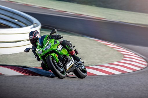 Three-quarter front angle of a person riding a motorcycle on a racetrack. opens in a new window