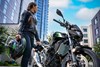 Three-quarter front angle of a person standing next to a motorcycle.