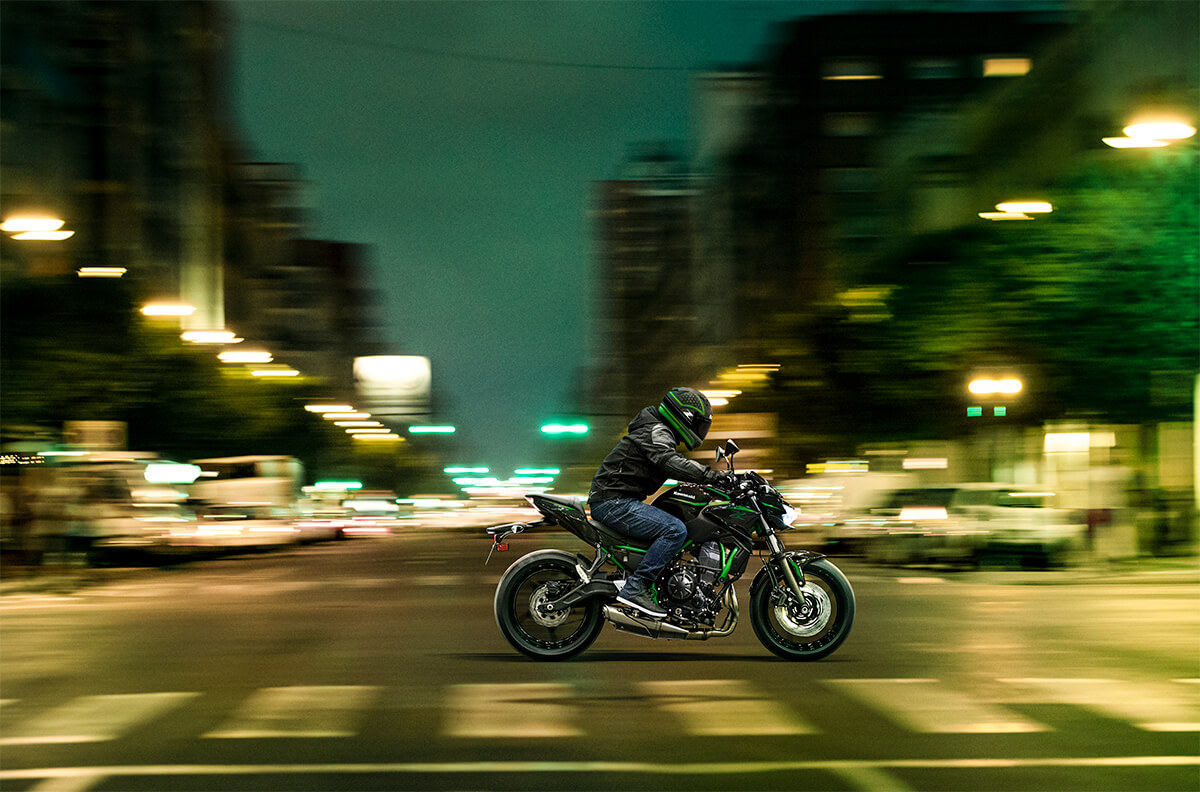 Side angle of a person riding a motorcycle on the street.
