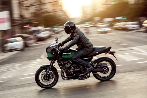 Side angle of a person riding a motorcycle on a city street. opens in a new window
