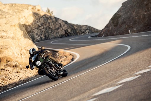 Three-quarter front angle of a person riding a motorcycle on a highway. opens in a new window