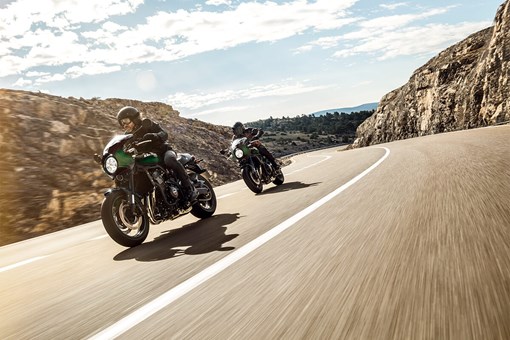 Three-quarter front angle of two people riding motorcycles on a highway. opens in a new window