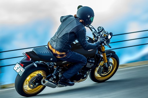 Three-quarter rear angle of a person riding a motorcycle on a highway. opens in a new window