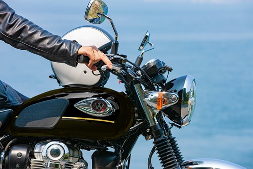 Close-up side angle of a motorcycle handlebar and helmet. opens in a new window