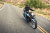 Three-quarter front angle of a person riding a motorcycle on a highway.