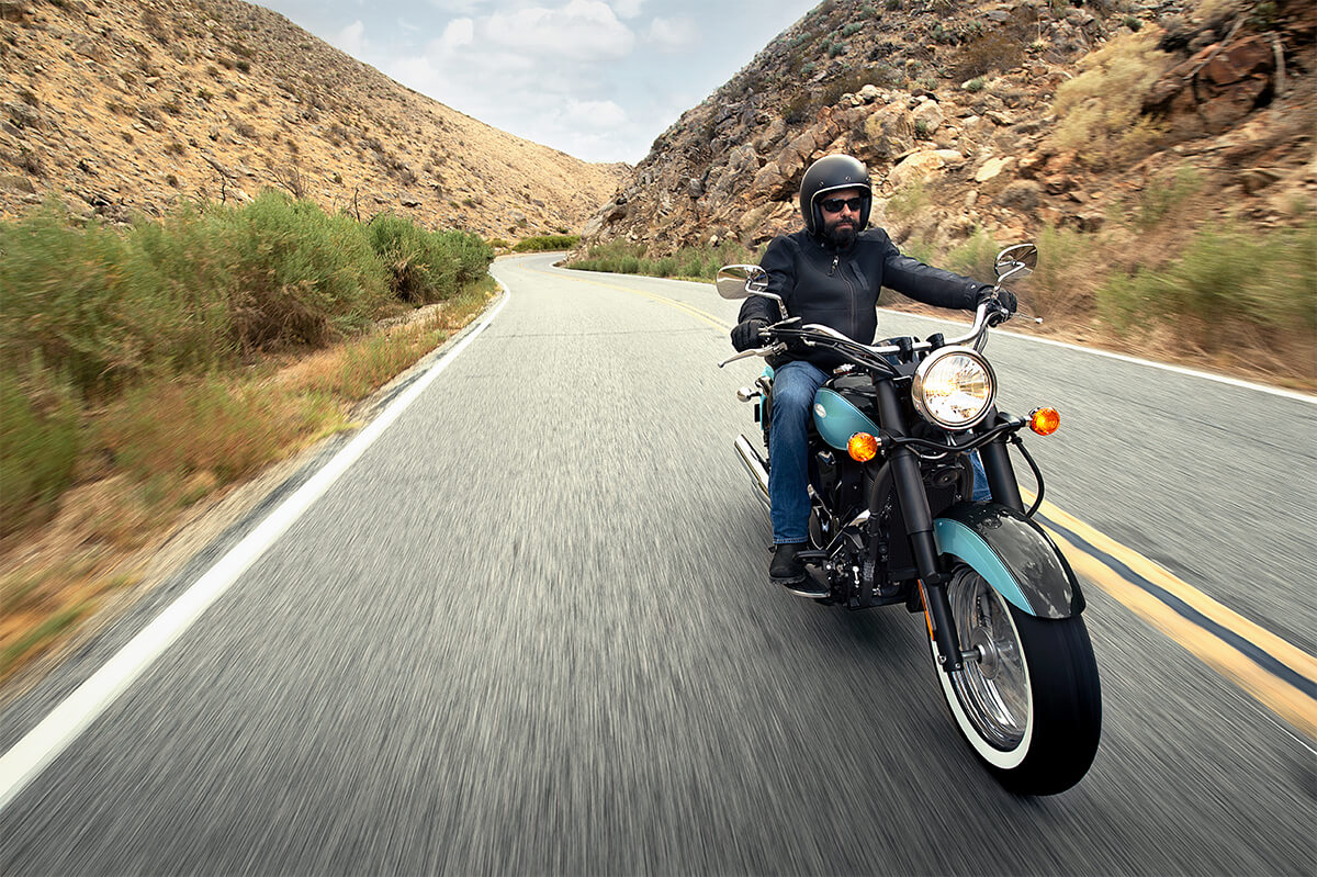 Three-quarter front angle of a person riding a motorcycle on a highway.
