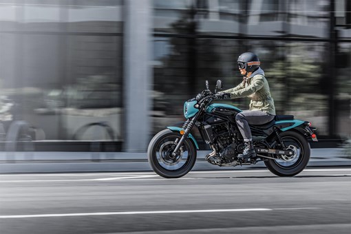 Side angle of a person riding a motorcycle on a city street. opens in a new window