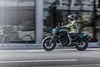 Side angle of a person riding a motorcycle on a city street.