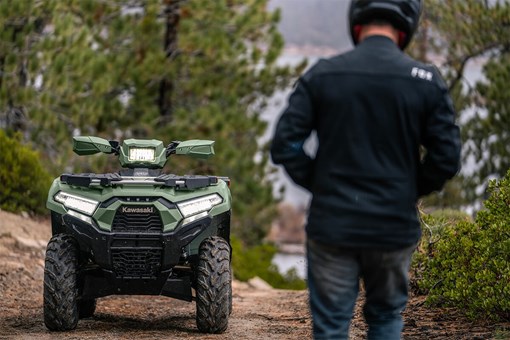 Front view of an ATV parked off-road with a person in the foreground. opens in a new window