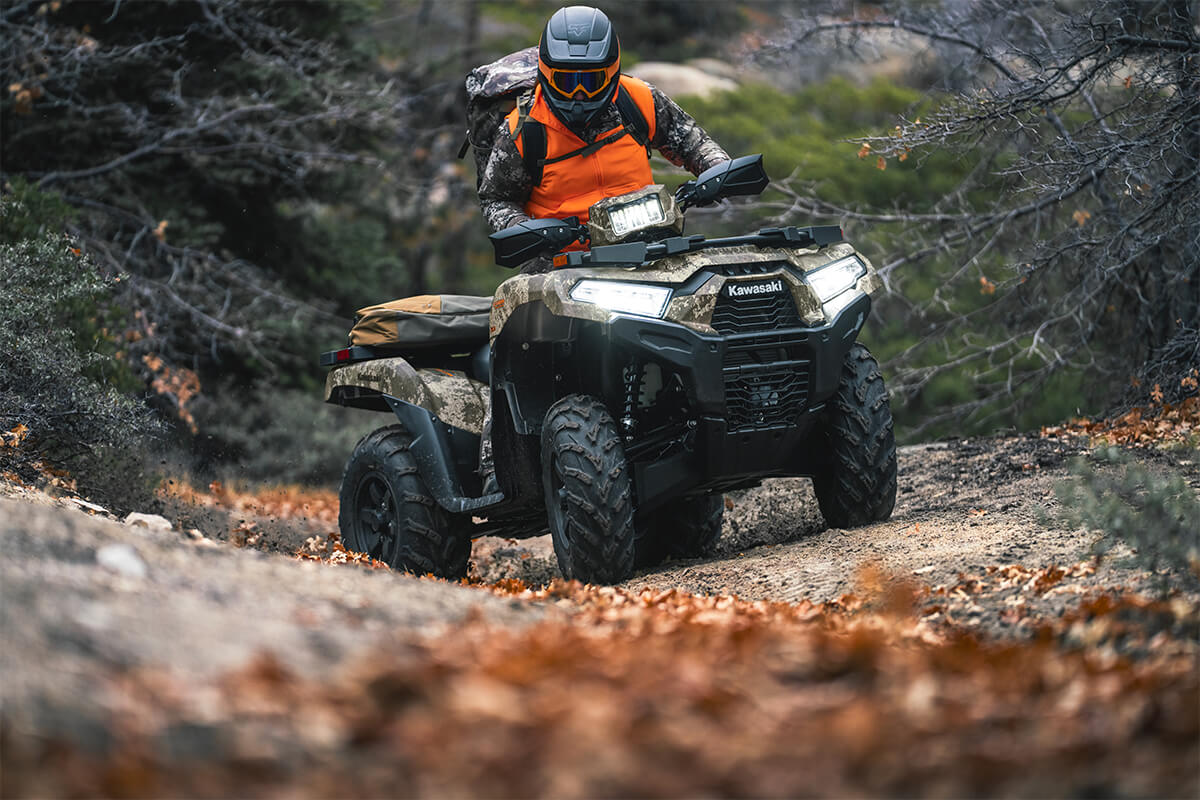 Front three-quarter view of a person riding an ATV off-road.