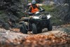 Front three-quarter view of a person riding an ATV off-road.