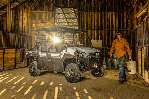 Three-quarter front angle of a parked side x side and a person carrying a bucket. opens in a new window