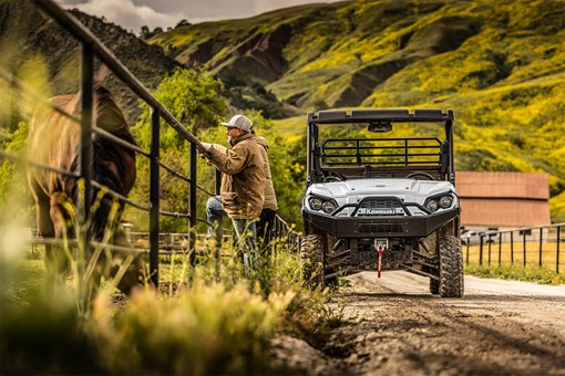 Front angle of a side x side parked on a farm near a horse and person. opens in a new window