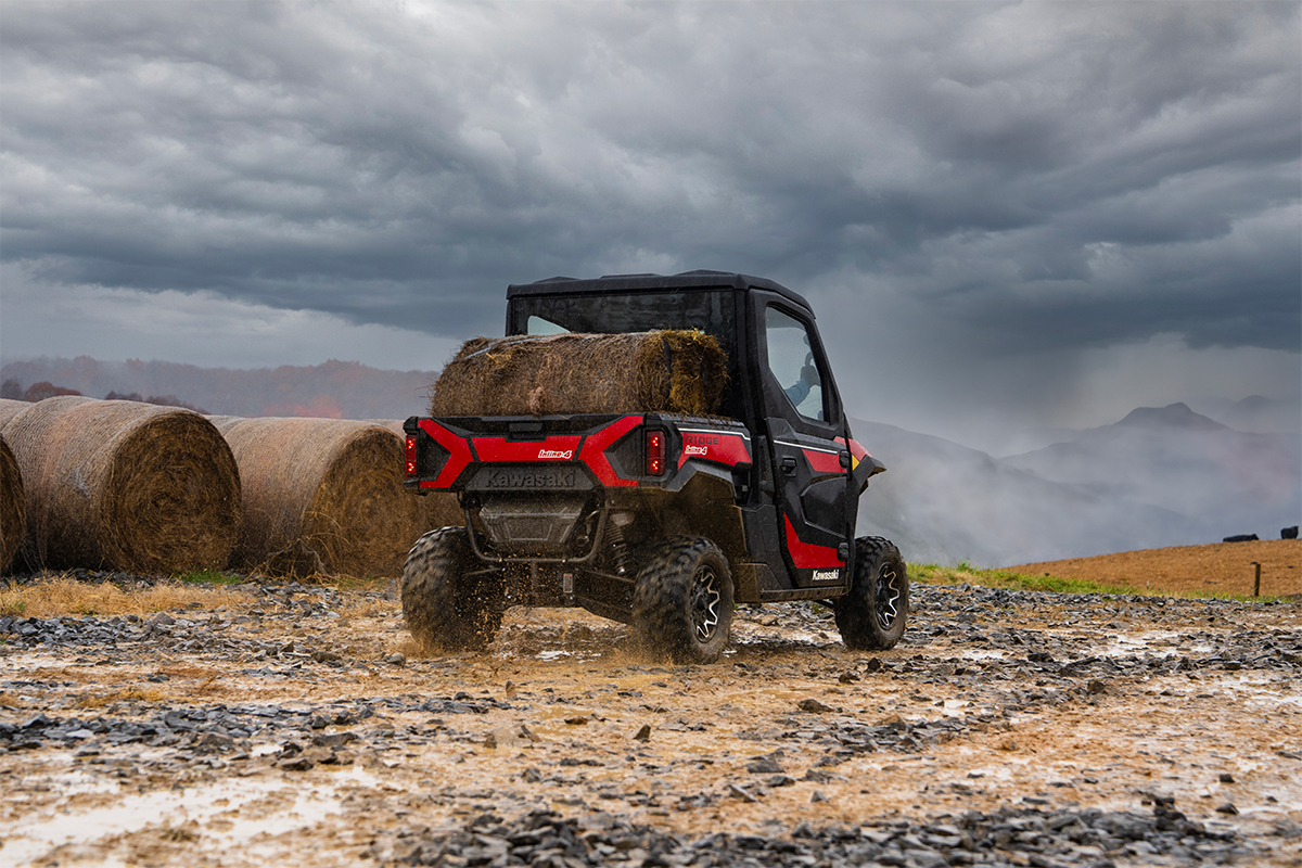 Rear view of a person driving a side x side with a load in the cargo bed. 