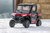 Front view of a person driving a side x side through the snow. 
