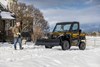 Front three-quarter view of a side x side with a snow plow attachment. 