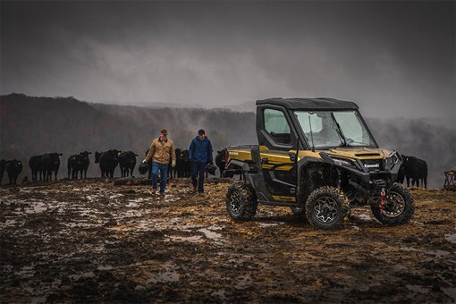 Front three-quarter view of a side x side parked next to ranchers and a herd of cattle. opens in a new window