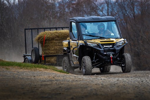 Front three-quarter view of a side x side towing a load of hay.  opens in a new window